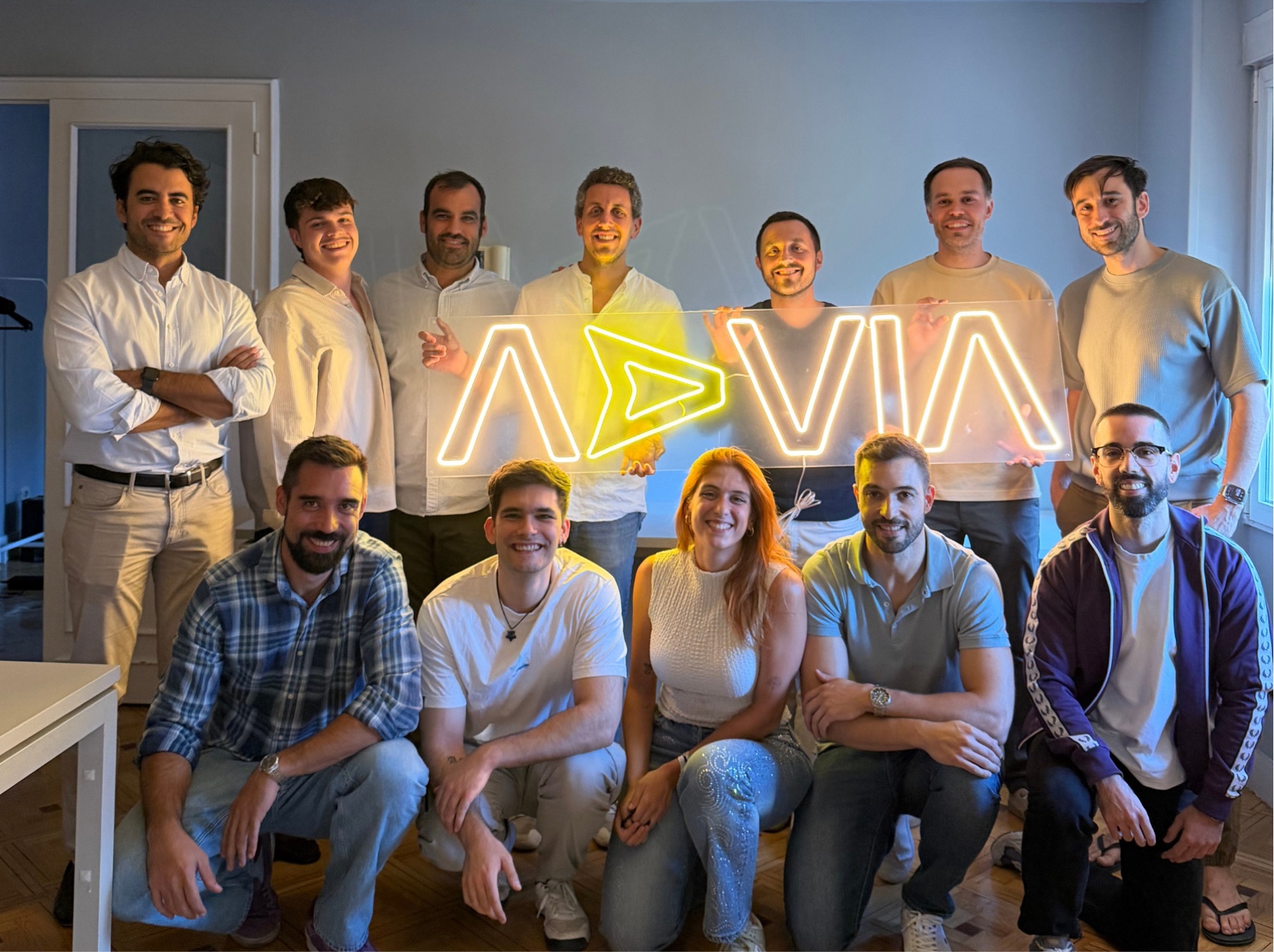 The whole Advia team in the Madrid office, with the brand's neon sign